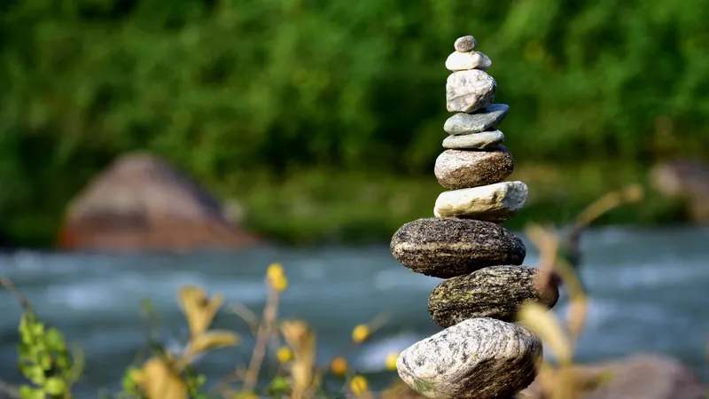 A cairn of river stones balanced beside fast moving water, restlessness that is a signal to be followed rather than a fault to be corrected